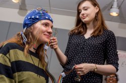 Person attaching wires to a sensor cap worn by a student