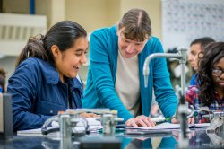 A professor and a student smiling while checking observations in a chemistry lab