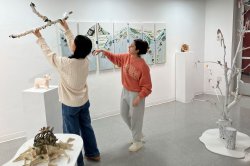 two students in a gallery, one student holding a sculpture up