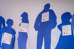 Blue, life-size cutouts of people are displayed in a university hallway. Each cutout symbolizes an individual who is a victim of human trafficking to raise awareness to the issue