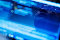 A student's face reflected off an out-of-focus laptop screen