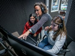 Professor Maria Jose Garcia Vizcaino with two students in an audio booth for a Spanish Audio Description and Translation class.