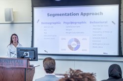 Student presenting in a classroom, standing in front of a projection screen