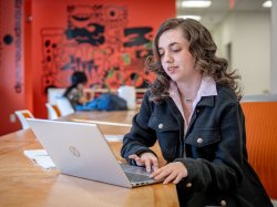 Student in business attire working on a laptop
