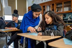 A teacher helps a student with a class assignment.