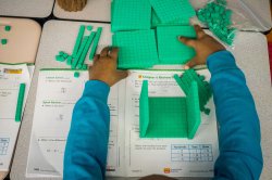 Overhead view of a child working with green blocks to learn the fundamentals of subtraction.