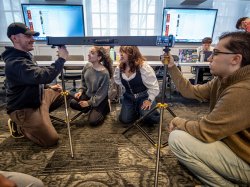 Students and professor setting up film equipment together.