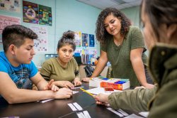 A teacher helps students with a group project.