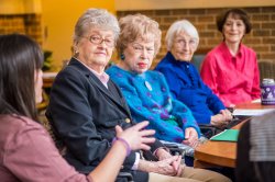 A Montclair student out of focus in the foreground speaks with a group of senior citizens.