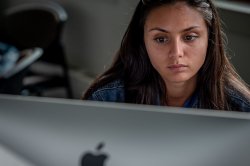Close view of a woman's face as she looks at a monitor which is in the foreground