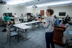 An educator speaks to a group of K-12 students in a classroom setting.