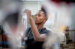 Student in scrubs checks and I.V. fluid bag.