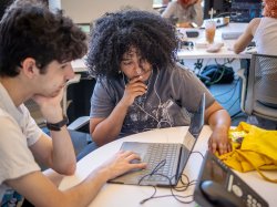 two students working together looking at a laptop