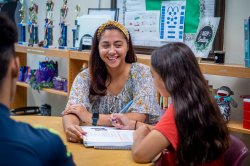 A teacher works on reading with a younger student.