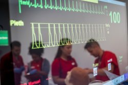 heart rate and blood oxygen on a screen reflecting nursing students wearing red scrubs