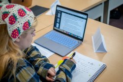 Student writing in notebook during writing workshop