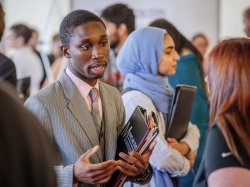 Student in business attire, speaking to a company representative at job fair