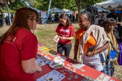 A student at an outdoor fair hands out information about nutrition to attendees