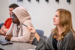 Students in a classroom, pointing with a pen