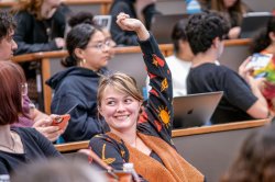 Student in classroom with hand raised