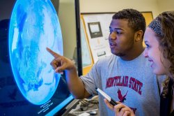 Two students standing in front of an interactive display using Google Earth