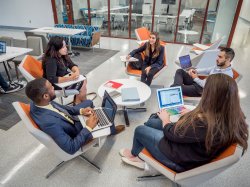 five students in conversation, sitting in lounge chairs arranged in a circle