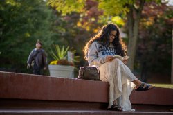 Student reading a book, sitting on a ledge on Montclair campus