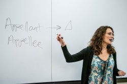Professor Jessica Henry stands before a white board, speaking to class