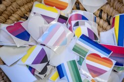 A basket holding LGBTQ+ pride stickers shaped as flags and hearts.