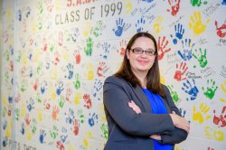 An educational administrator poses in front of a decorated school wall.