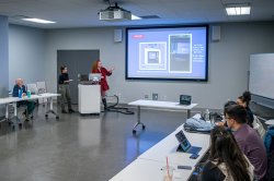 Communications students presenting in front of a projection screen
