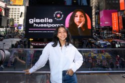 Giselle Huasipoma stands in front of a digital billboard in Times Square