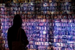 Student stands in front of an illuminated wall displaying an array of burial sites