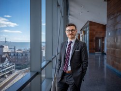 Kyle Peters towards the camera as he stands near a window.