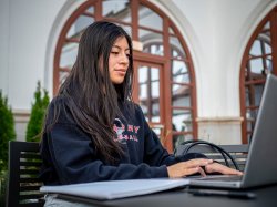 Montclair State University student working on a laptop outside.