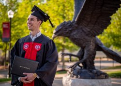 Student smiling in cap and gown holding diploma