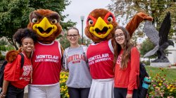 students pose with Rocky and Roxy the red hawks, wearing Montclair sweaters