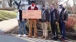 Alumni pose with student and scholarship check