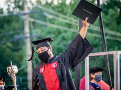 Photo of student at graduation holding diploma up
