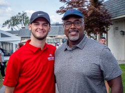 student and alumnus smiling at golf outing