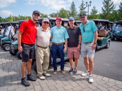 golfers pose for photo in front of golf carts