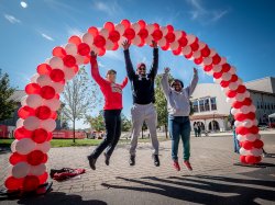 alumni jumping under balloon arch