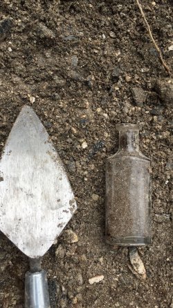 Bottle and spade in dirt
