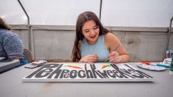 Farrah Fornarotto, a junior majoring in Anthropology, with minors in Archaeology and Native American and Indigenous Studies, paints a garden sign with the Munsee language word for "carrot."
