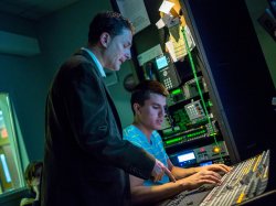 David Sanders assisting student with audio mixing board