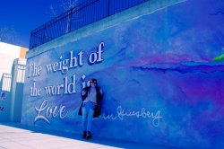 Student in front of mural that reads "The weight of the world is love"