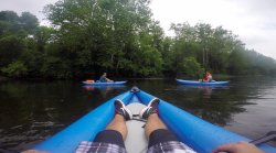 View from a the perspective of someone in a kayak, looking at two other kayaks on a river