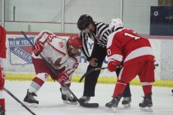 Two hockey players about to face off, and a referee in the middle of them