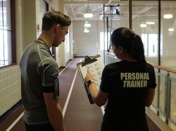 A personal trainer showing a patron their fitness chart on the indoor track.