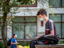 Photo of a student wearing a face mask and sitting outside.
